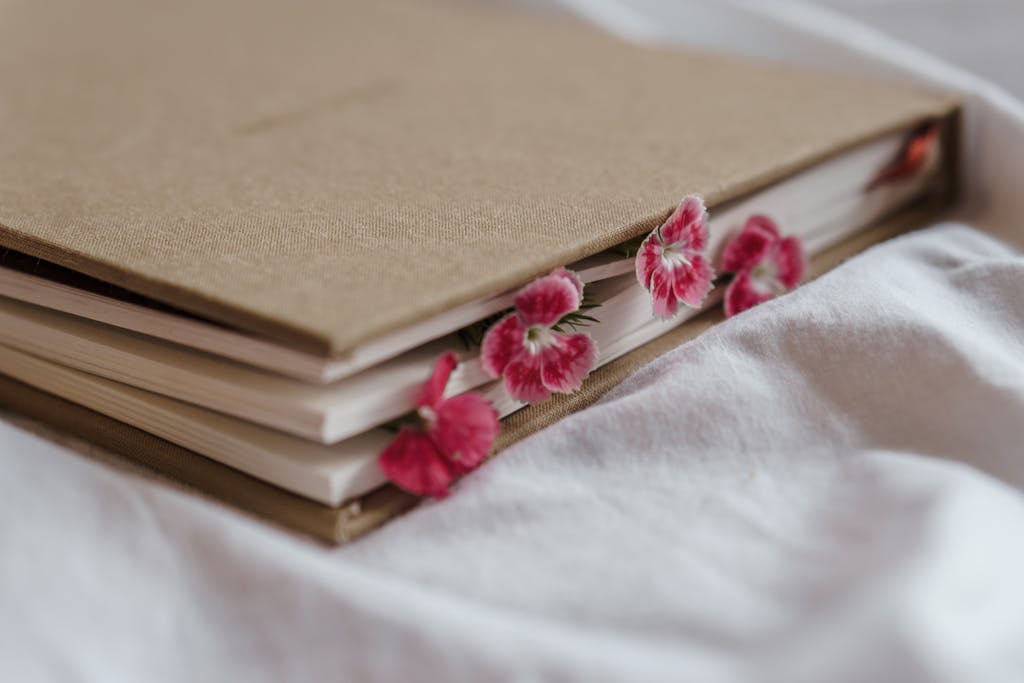 A beautiful beige journal adorned with pink floral bookmarks resting on soft white bedding.