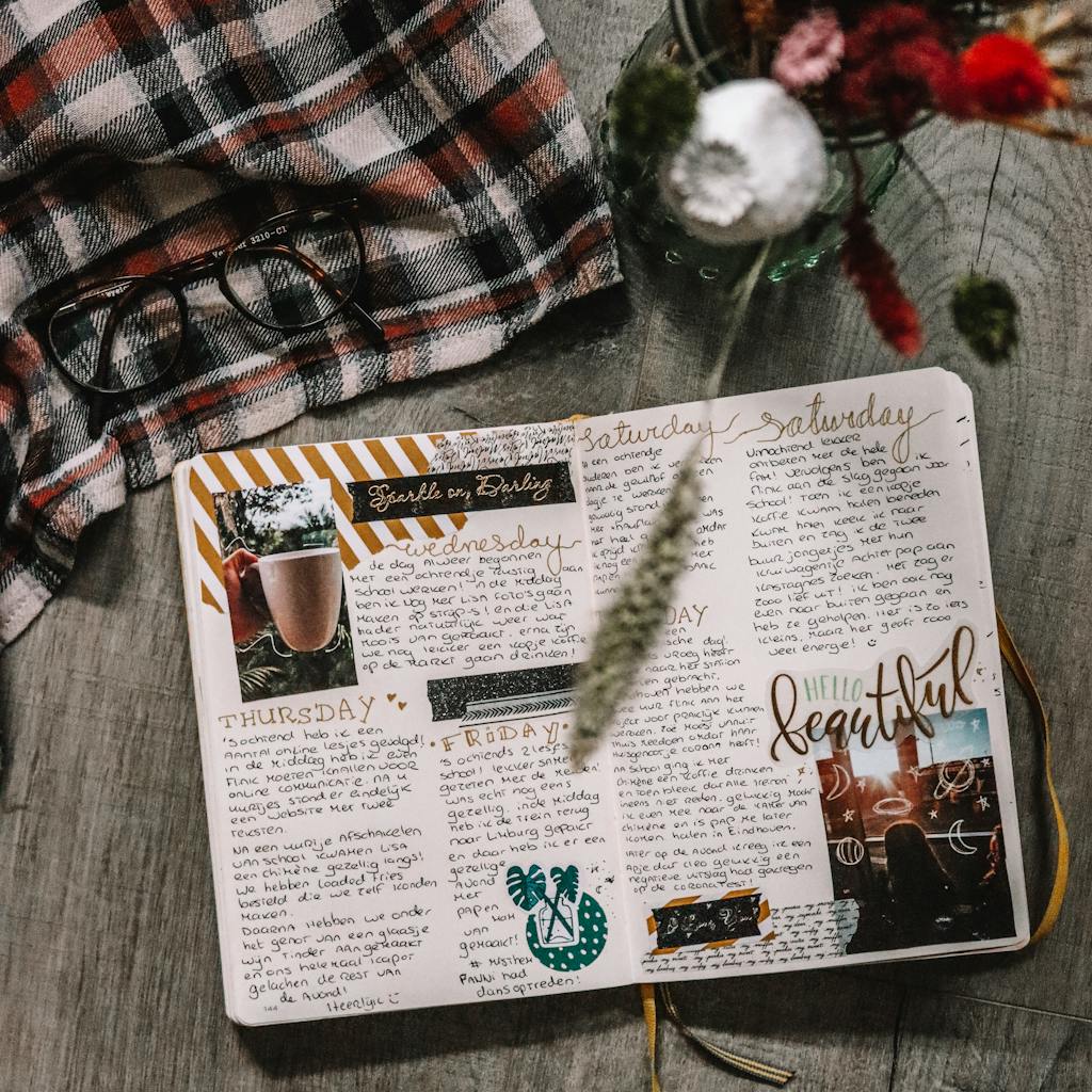 Top view of a diary surrounded by eyeglasses, fabric, and flowers, perfect for a cozy and artistic lifestyle.