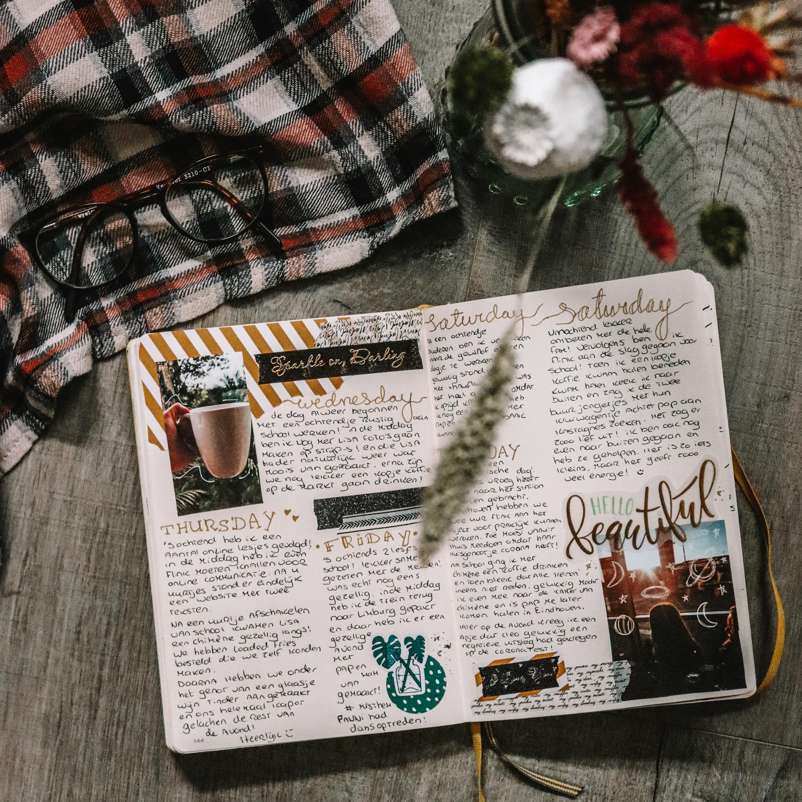 Top view of a diary surrounded by eyeglasses, fabric, and flowers, perfect for a cozy and artistic lifestyle.